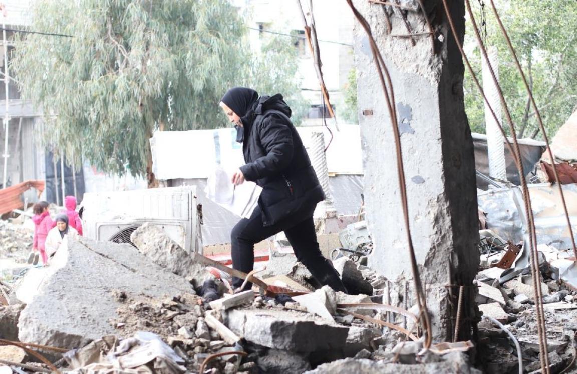 A lady walking through rumble of destroyed building in Gaza